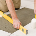 Home improvement, renovation - handyman laying tile with level
